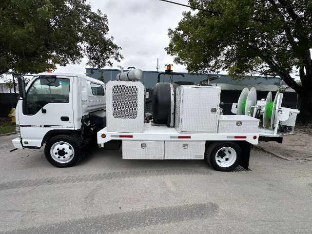 GMC W5500 vacuum truck side view with service compartments and reels.