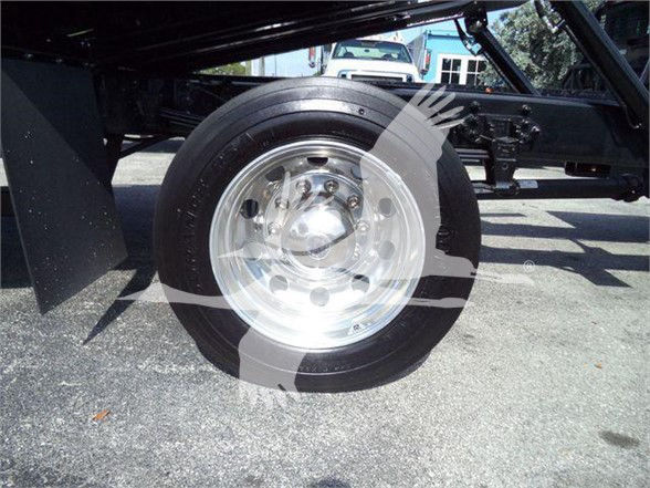 Wheel with polished metal hubcap and tire mounted on a heavy-duty trailer; undercarriage and frame visible.