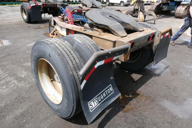 Trailer dolly with dual rear wheels and mud flaps showing 'STOUGHTON' branding; rear frame, hoses, and license-plate area visible.