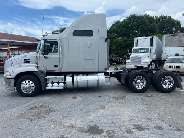 2010 Mack CXU613 conventional sleeper truck side view showing cab, fuel tanks, and dual rear axles.