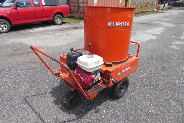 Tractor-towed Kubota fertilizer/seed mixer with orange hopper and small engine on a wheeled cart.