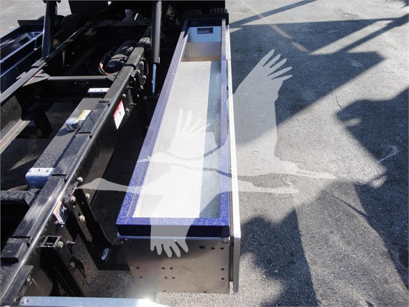 Peterbilt 337 chassis with a rectangular metal slot/step assembly extending from the frame side, showing a purple-trimmed edge and shadows on the ground.