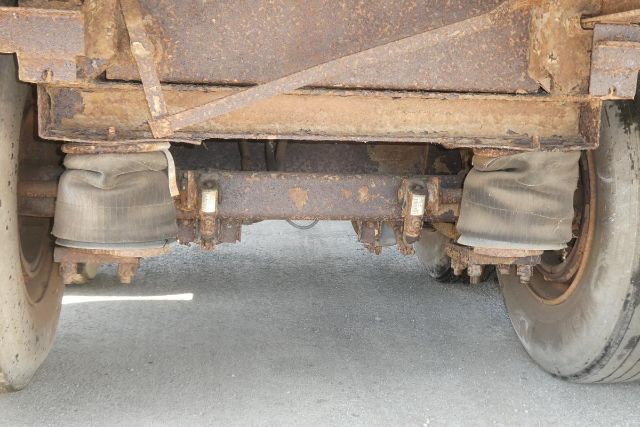 Rear underside of a Fruehauf trailer showing suspension and wheel assemblies with mud and wear.