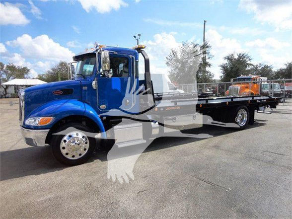 Peterbilt 337 tow truck in blue with long flatbed, chrome wheels, cab and rear section visible.