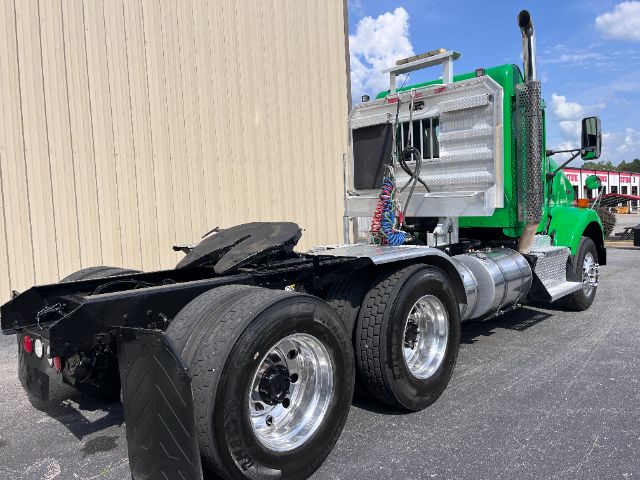 Kenworth T800 truck chassis rear and cab side showing green cab, chrome fuel tanks, dual rear axles, and fifth wheel area with exposed components.