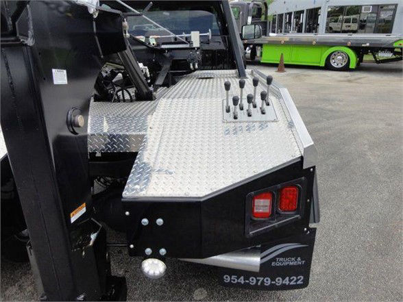Ram 4500 tow truck rear deck with diamond plate platform and multiple control levers, taillights, and rear bumper with contact number 954-979-9422.