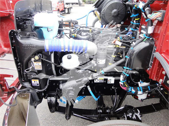 Front view of a 2022 Peterbilt 337 truck engine bay with blue sleeve hoses, wiring harness, radiator, and various components visible.