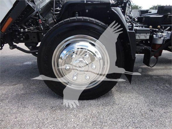 Isuzu NRR truck front wheel and chrome hubcap visible in foreground with suspension components.