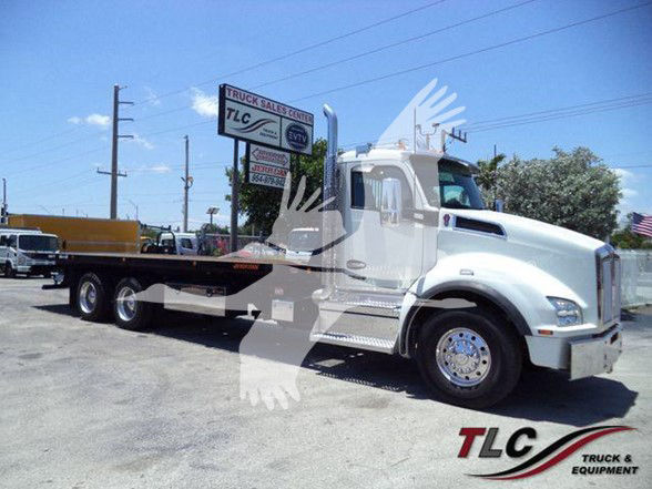 Kenworth T880 flatbed tow truck in a dealership lot, side view showing front grille, chrome wheels, and TLC Truck & Equipment logo in bottom right corner.