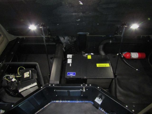 Kenworth T680 cab and chassis engine bay area with battery box and wiring; visible labels and a red fire extinguisher mounted on the right.