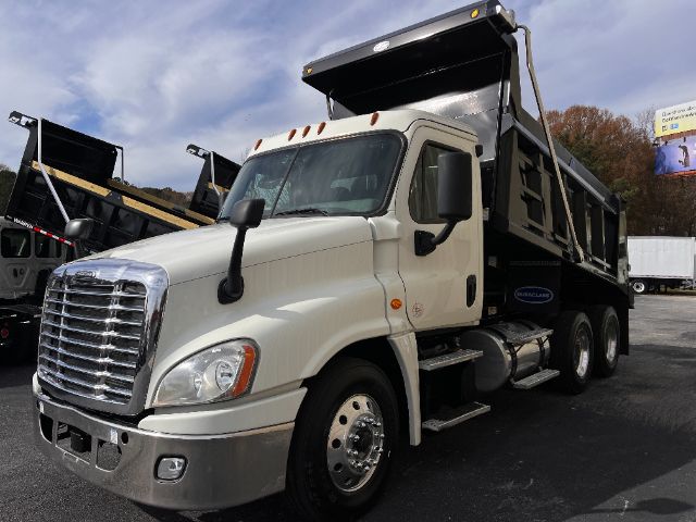 White Freightliner Cascadia 2019 dump truck with a raised dump bed, chrome grille, large side mirrors, and front bumper. Dual rear wheels visible, truck parked in lot.