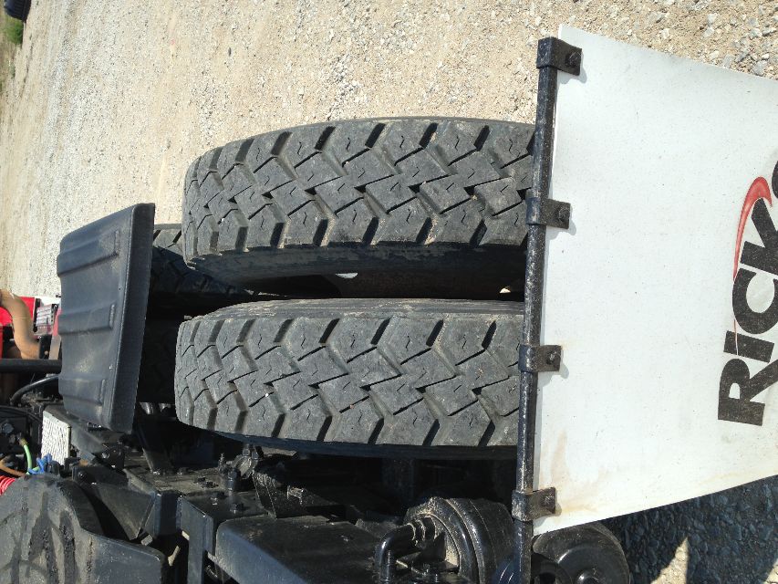 Dual rear tires on a Kenworth truck chassis with a white Rick trailer sign in the foreground.