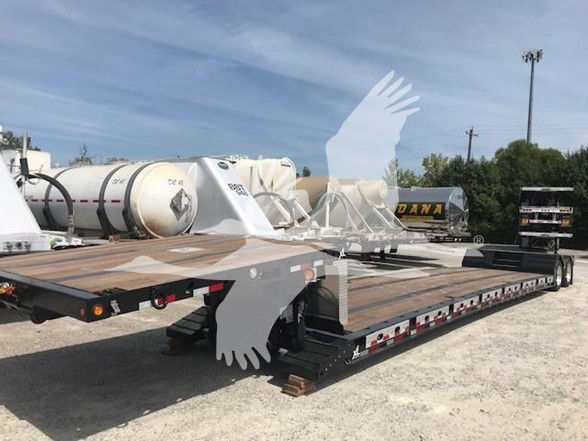 XL Specialized trailer with aluminum pullouts on a flatbed trailer in a gravel lot, various tanks and trailers in background.