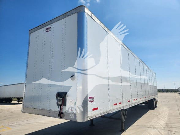 Trailer side view showing plain silver Wabash dry van with riveted aluminum panels, rear mud flaps, and landing gear.