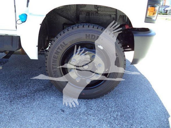 Truck wheel well of a 2023 Chevrolet Silverado 6500HD with large Continental HD tires and white body panel, partial headlight area visible.