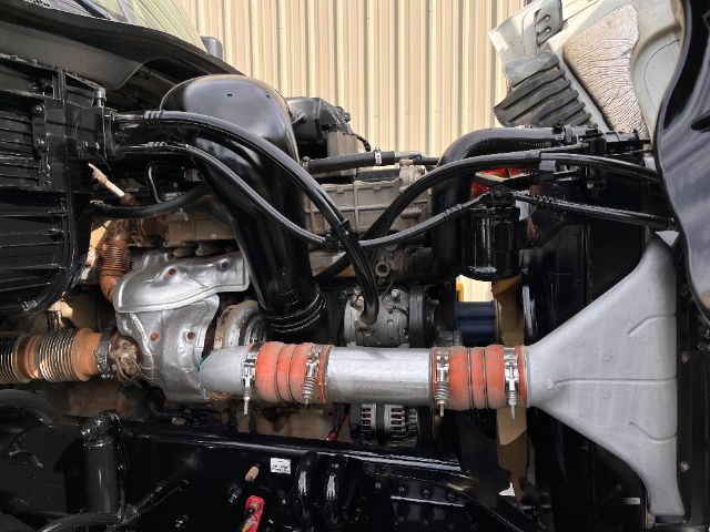 Engine bay showing intake manifold, hoses, turbocharger, and coolant lines in Freightliner Cascadia truck.