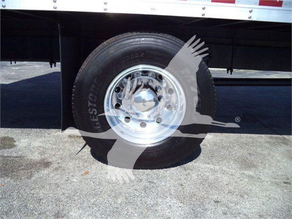 Wheel and tire of a Mack MD6 box truck showing polished chrome hubcap and tire treads.