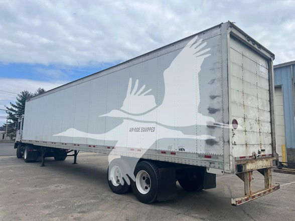 Great Dane sheet and post roll door trailer with white and gray bird graphic on side and rusty rear doors.