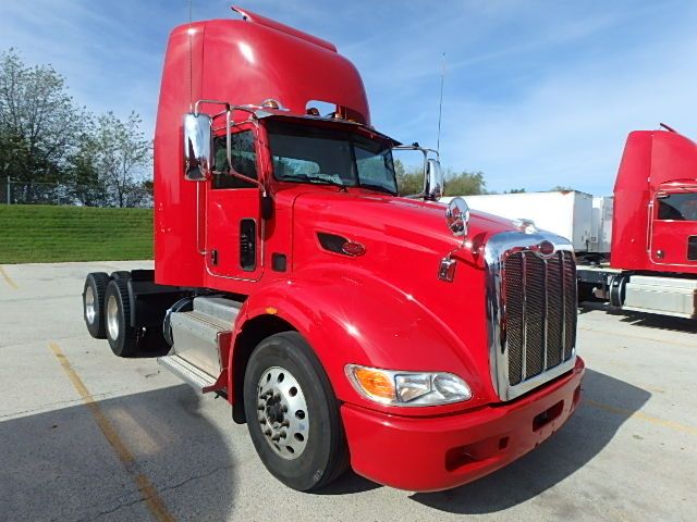 Peterbilt 386 tractor in red, front three-quarter view, chrome grille, dual exhaust, large windshield, sleeper cab behind visible.