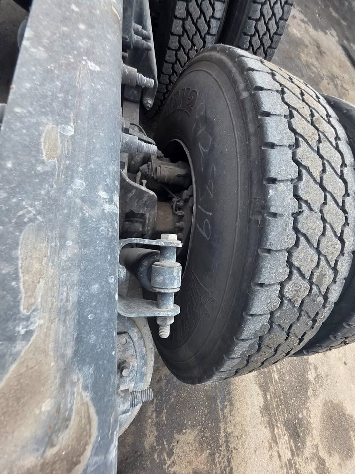Truck wheel and front suspension showing large heavy-duty tire and steering/axle components.