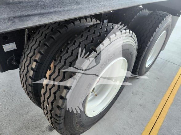 Dual rear axles with heavy-duty tires and white rims. Visible text on the side shows VIN and stock details overlaying the image.
