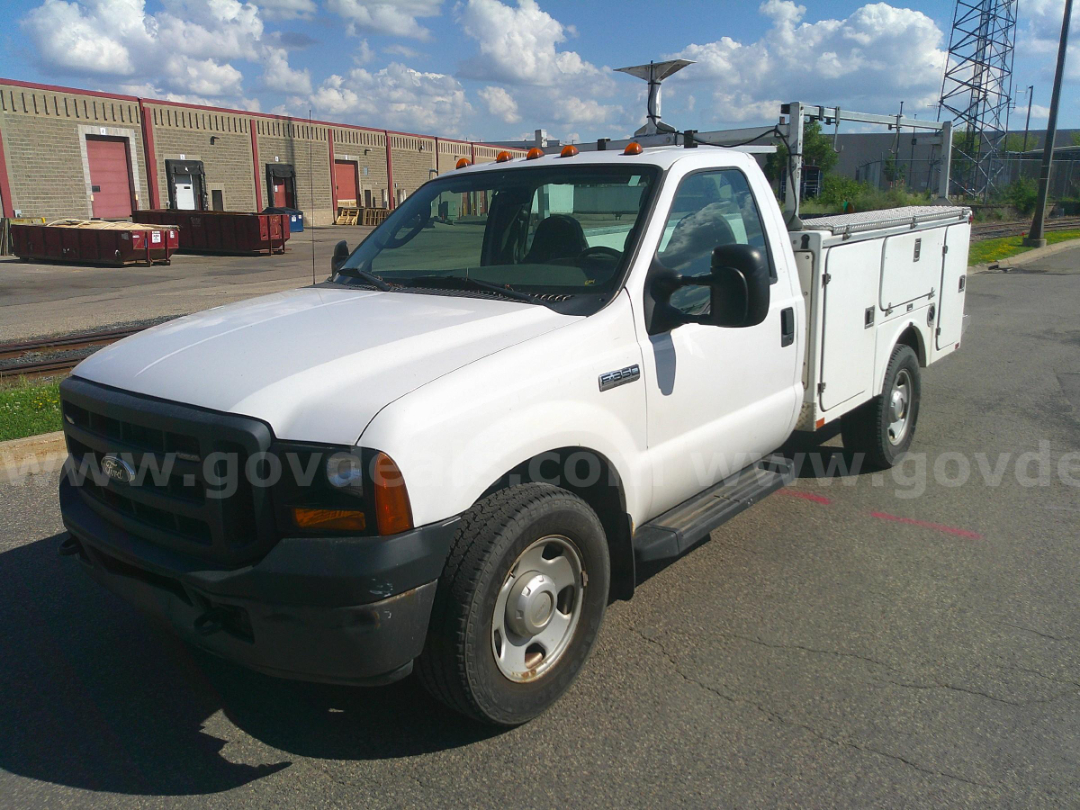 Ford F-350 utility/service body truck in white, front-left view with utility compartments along the bed.