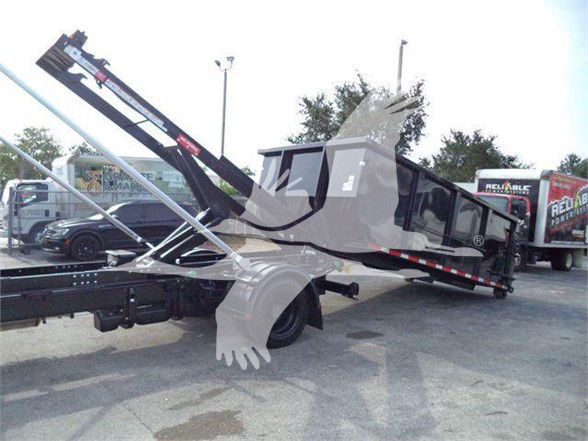 Truck bed with hydraulic hoist and tilt, rear view showing Silverado 6500HD style cab and chassis, with guard rails and chain hoist in an outdoor lot.