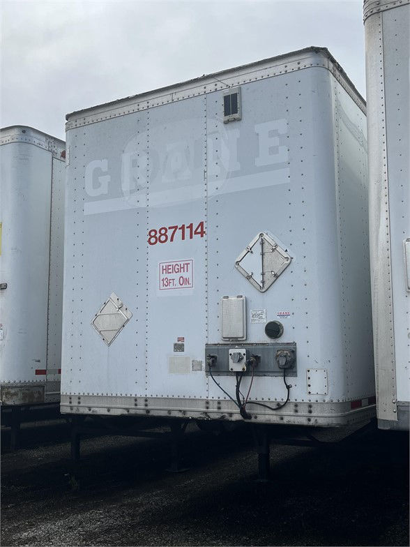 Rear view of a white Wabash dry van trailer showing the number 887114, two safety placards, and utility connections at the lower rear with a height notice reading 13 ft 0 in.