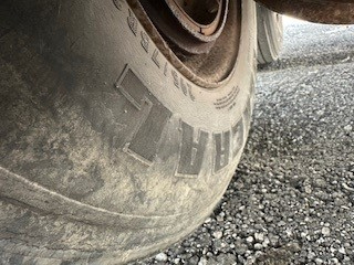Close-up of a tire on a trailer wheel showing worn tread and sidewall texture.