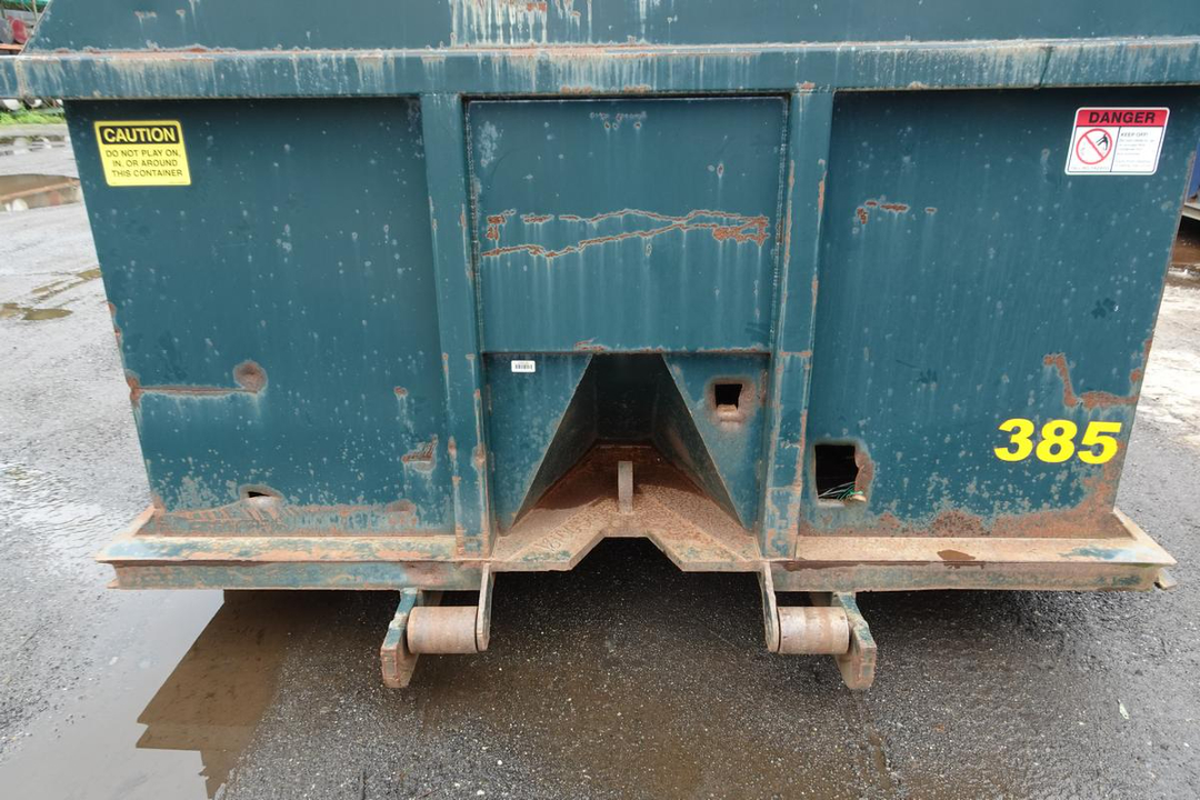 Wastequip 20 yd dumpster rear view showing chute and rear wheels with 385 number, caution and danger stickers.