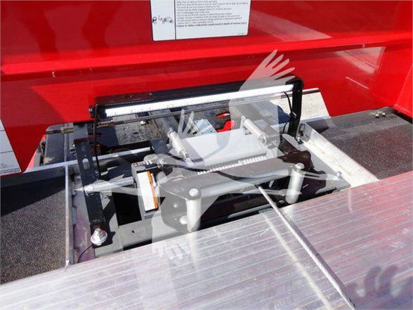 Tow truck chassis area showing a hydraulic or mechanical lift mechanism on a red Peterbilt 337 with control bars and metallic platform.