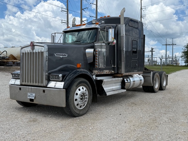 2012 Kenworth W900 tractor truck in black with chrome fuel tanks and dual rear axles, front grille, and tall sleeper cab.