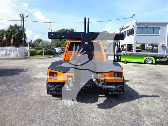 Back view of a bright orange Ram 4500 SLT tow truck with a large black boom/tower and towing hooks. License plates and text on rear bumper area visible.
