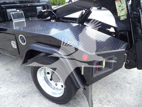 Ram 4500 tow truck bed with diamond plate toolbox and wheel, side view showing fuel cap and rear fender.