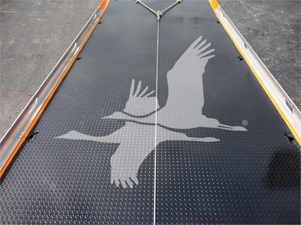 Deck of a 2022 Peterbilt 337 tow truck with a large bird logo on the diamond plate metal floor; part of a trailer or ramp with orange and silver edges.