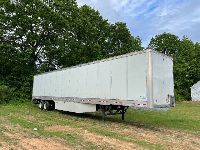 A 53 ft Vanguard trailer with a silver exterior, parked on grass and trees in the background.