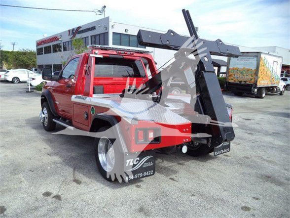 Red 2024 Ram 4500 SLT tow truck with a hydraulic arm and wheel lift visible in rear, dealership lot in background.