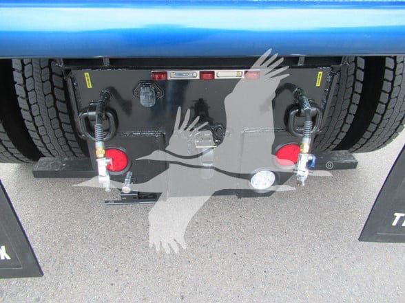 Kenworth T380 rear view showing chassis, hoses, and mounting plate with warning labels and taillight areas.
