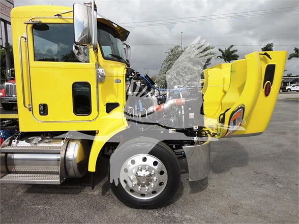 Front-left view of a bright yellow 2022 Peterbilt 337 tow truck with cab open at the hood and exposed engine area.