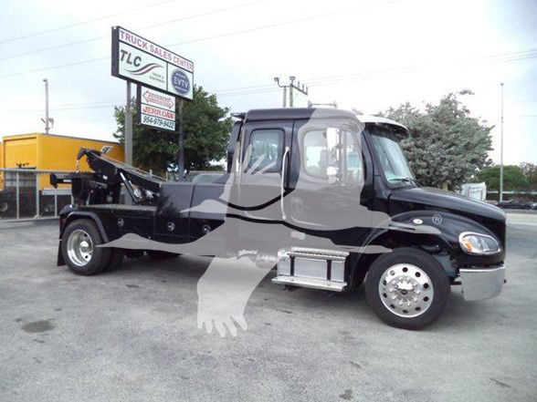 Tow truck chassis with black cab and chrome wheels showing tow equipment and hydraulic boom in a dealership lot.