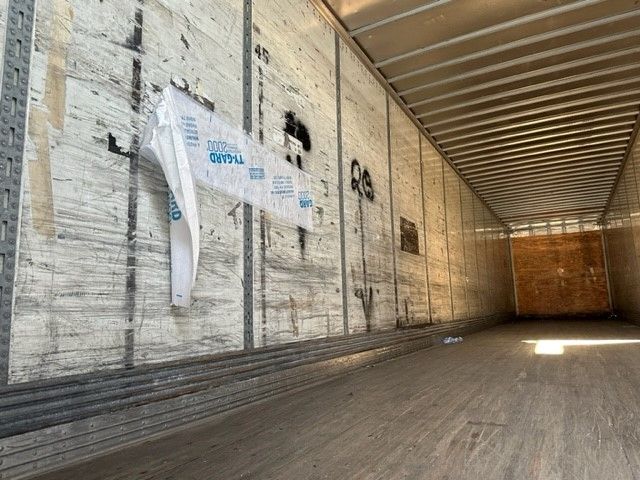 Interior of an empty Wabash trailer with Duraplate walls, side entry doors, and wooden end gate visible at far end.
