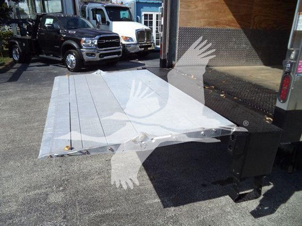 Isuzu NRR truck bed ramp/platform with reflective glare showing at a dealership lot.