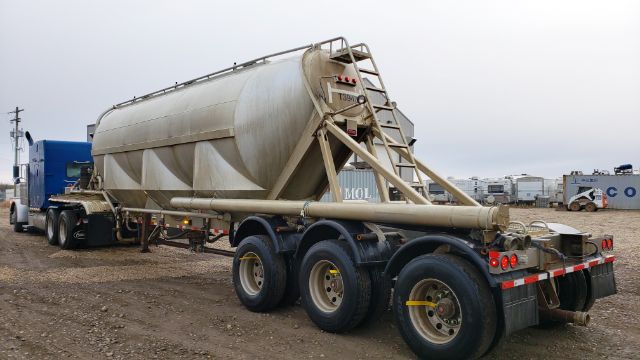 Trailered tank trailer with cylindrical aluminum tank on tri-axle with rear ladder and support structure.