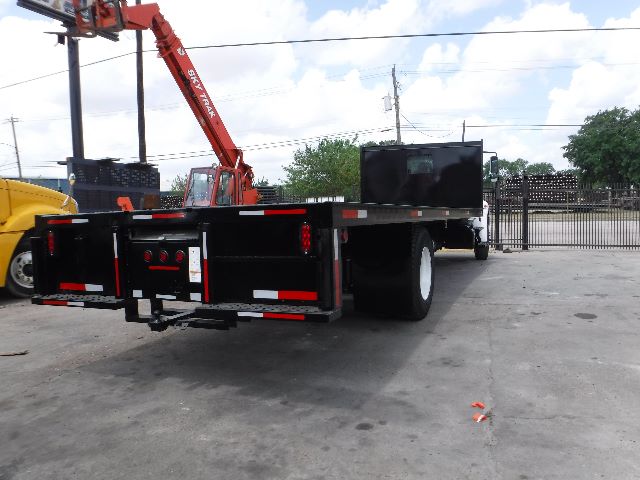2018 International 4300 flatbed truck with a black utility bed, viewed from rear-left, showing flatbed with tool compartments and rear lights.
