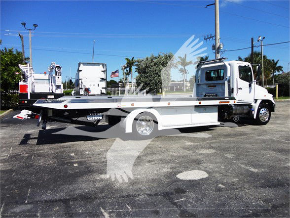 Tow truck chassis with flatbed in serviceable condition showing long aluminum deck and wheel hubs.