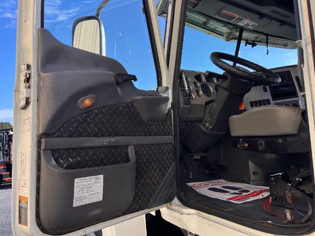 Cab interior of a 2013 Mack CHU613 Pinnacle truck with open driver door, dashboard gauges, steering wheel, and diamond plate door panel.