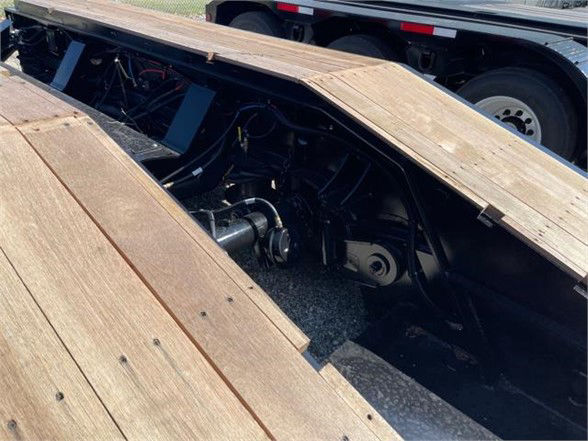 Deck of a Fontaine 55 ton steel roller paver lowboy trailer with wooden deck planks and visible hydraulic components under the deck.