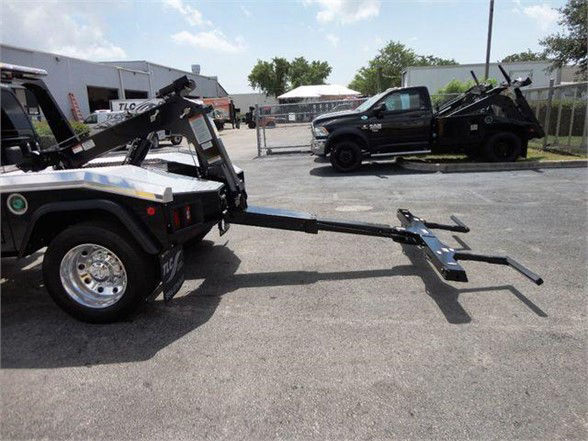 Ram 4500 HD tow pickup with a long hitch attachment extending from a tow bed; other tow trucks visible in background.