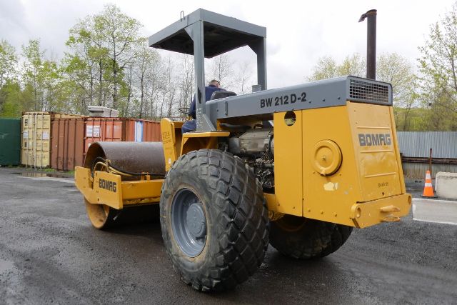 Bomag BW 212 D-2 soil compactor with large rear tires and smooth drum, yellow and gray color, operator cab, engine cover, and BW 212 D-2 labeling.