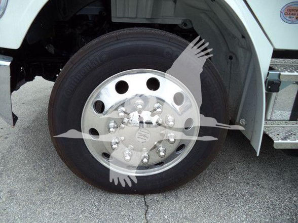Truck front wheel with chrome hubcap, tire, and part of white fender; faint watermark overlay.